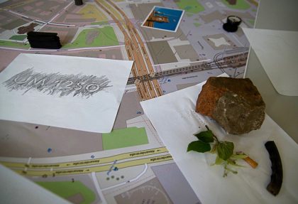 city map with rubbing drawings, a stone, leaves, a postcard and a cigarette butt