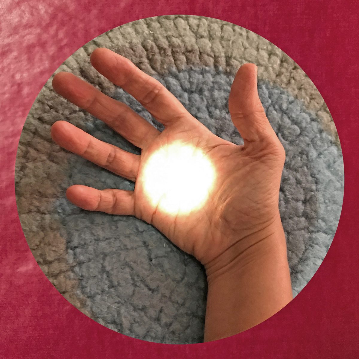 Open hand with the palm facing upwards in a blue-grey circle in a red square. There is a white circle of light in the centre of the palm.
